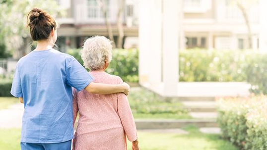 Elder person and nurse walking together
